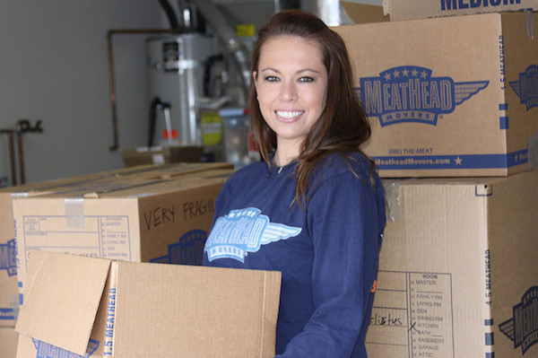 a woman is smiling while holding moving boxes