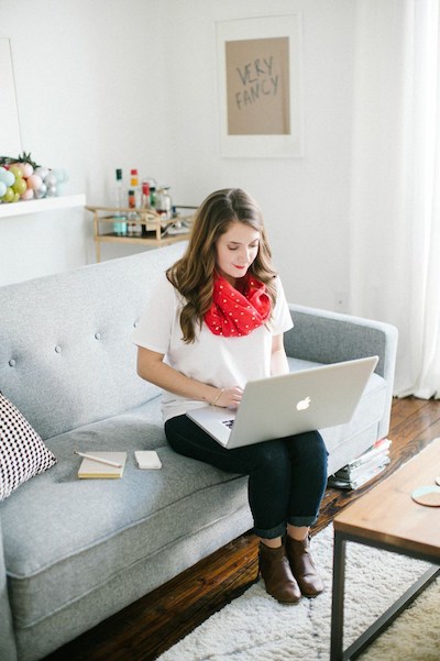 a woman sits on the couch with her computer