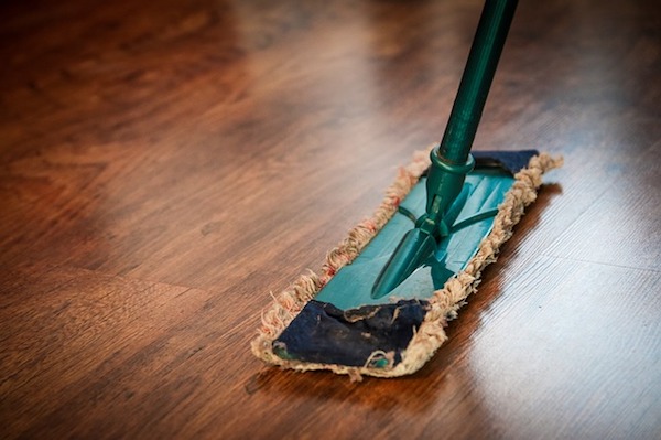 a green duster sweeps a hardwood floor