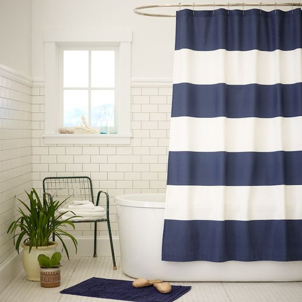 a white bathroom with a blue striped shower curtain