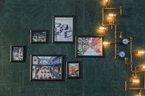 picture frames on a patterned wall being lit by lightbulbs