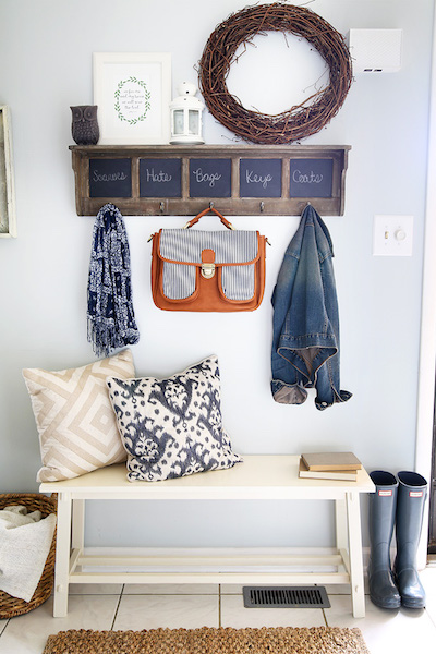 an organized mudroom with a couch and chalkboard coat rack