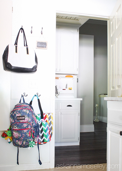 backpacks and other bags are hung on the wall with small hooks