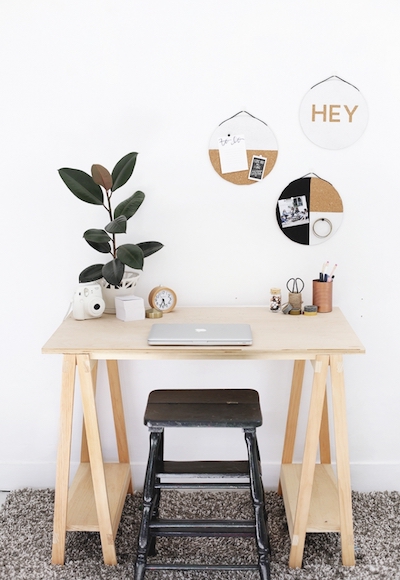 DIY cork boards hang above a desk with plants