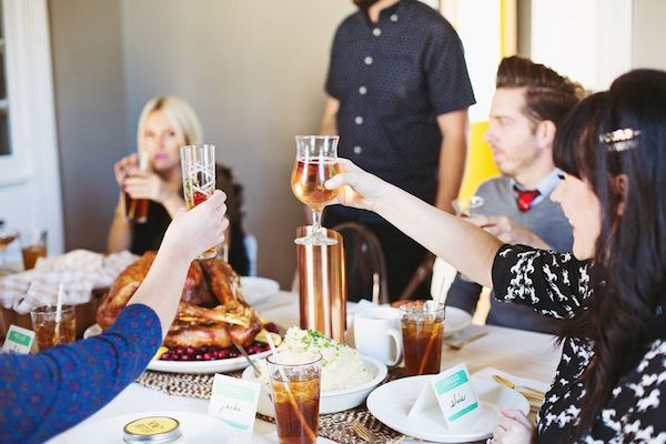 Friends gather for a Friendsgiving celebration and toast at the table