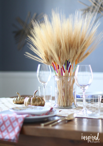 A stalk of wheat is wrapped with colorful strings on top of a Thanksgiving table