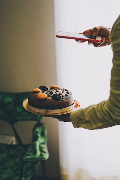 A person uses his phone to take a photo of a cake