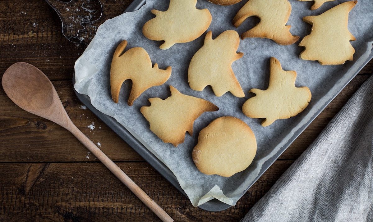 tray of holiday cookies next to a wooden spoon on a wooden table