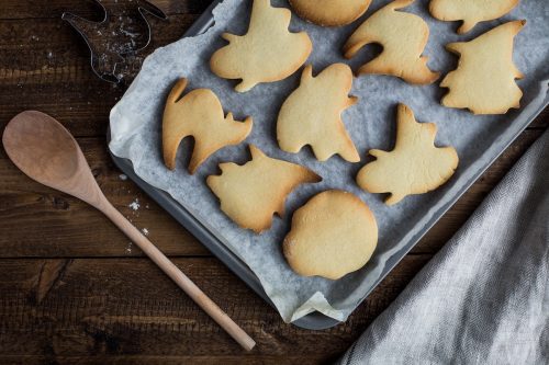 tray of holiday cookies next to a wooden spoon on a wooden table