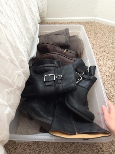 assorted boots stored in a clear storage bin without the lid