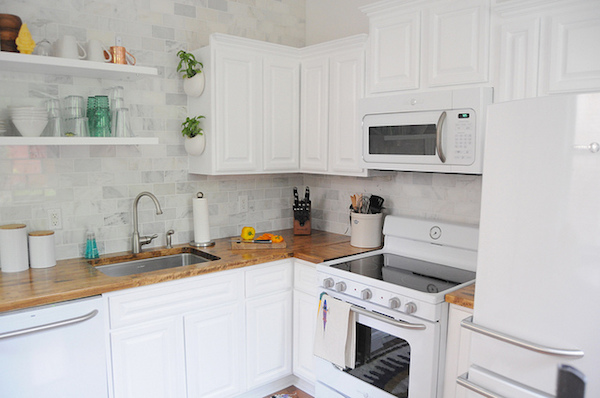A white, spacious kitchen with an oven and open shelving