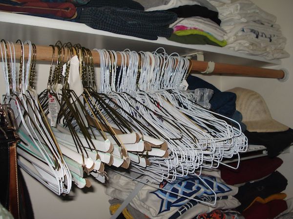 Old wire hangers are crammed together in a dimly lit closet 