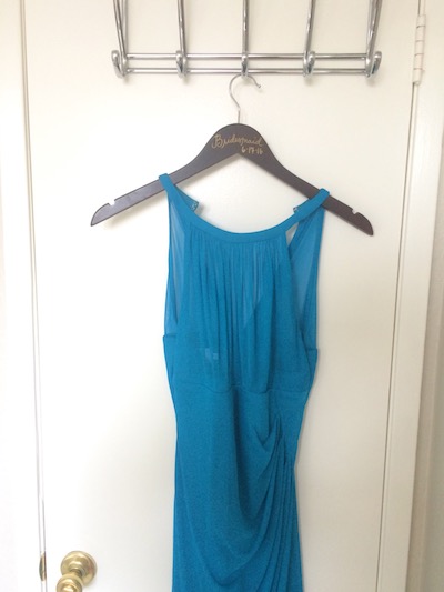 a formal blue bridesmaid dress hangs from the door, ready to be donated 