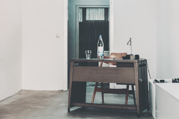 a nearly empty room with a desk and open doorway behind it