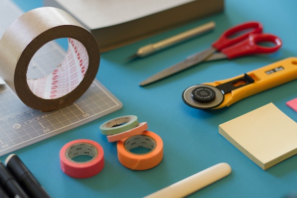 a table with office supplies like scissors, duct tape, and sticky notes