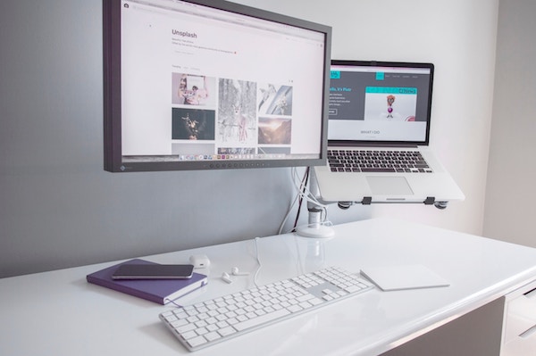 two computers are elevated to meet eye level