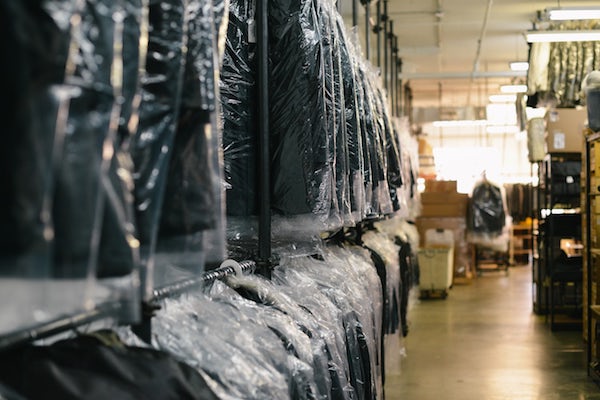 clothes in plastic dry cleaning bags are hanging on racks at the dry cleaners