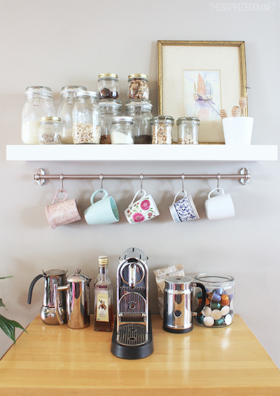 a small coffee station with a shelf and hanging rod that holds mugs