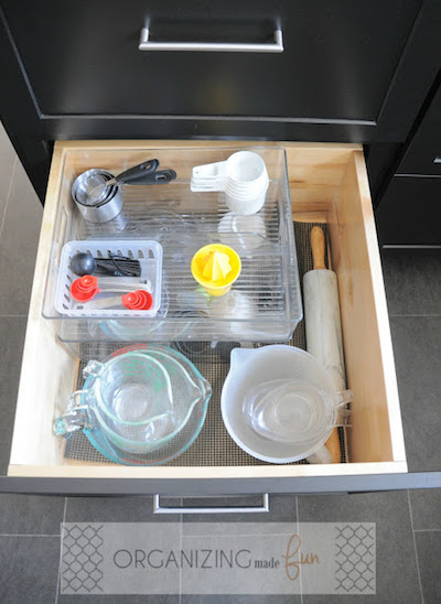 an organized kitchen drawer with items separated with clear containers and organizers