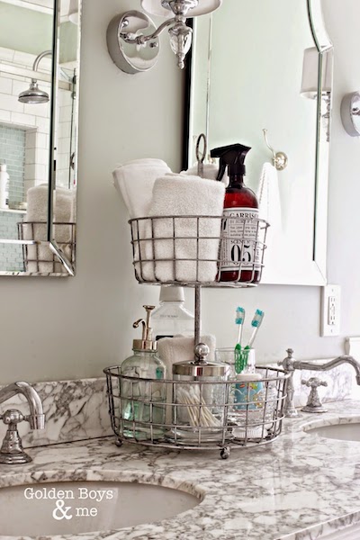 a two tiered wire basket organizer storing q-tips, toothbrushes, hand towels, mouth wash, and more