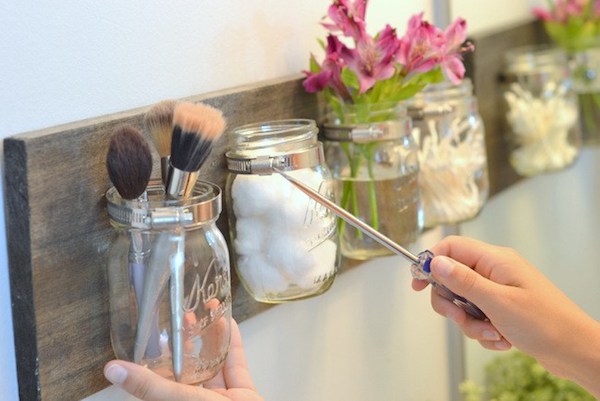 DIY mason jar organizers storing makeup brushes, cotton balls, flowers, and q-tips