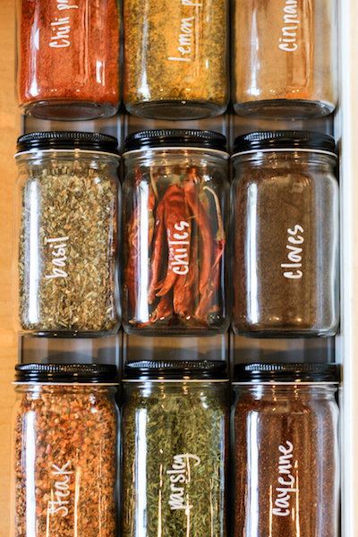 a spice drawer has been organized into uniform jars and labeled with a non-permanent marker