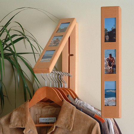 a clothes hanger pops out of a rebrilliant clothes hanging system, which looks like a photo frame hanging on the wall