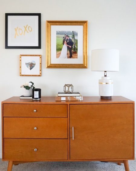 a classy gallery wall hangs above a large brown dresser