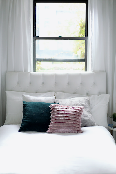 a bed is positioned under a window in a tiny apartment