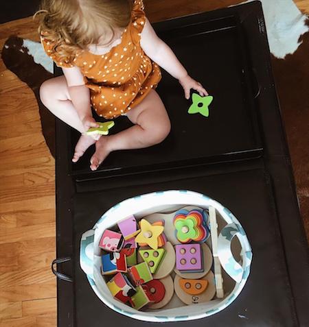 a little girl sits on a table with toys that have been put away