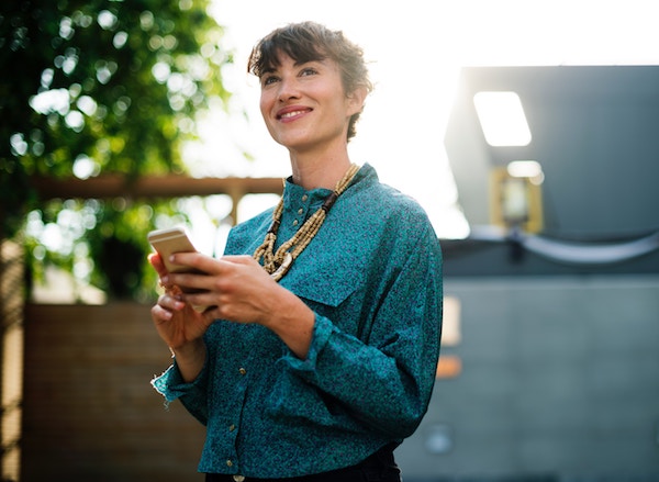 a woman smiles as she looks up from her phone