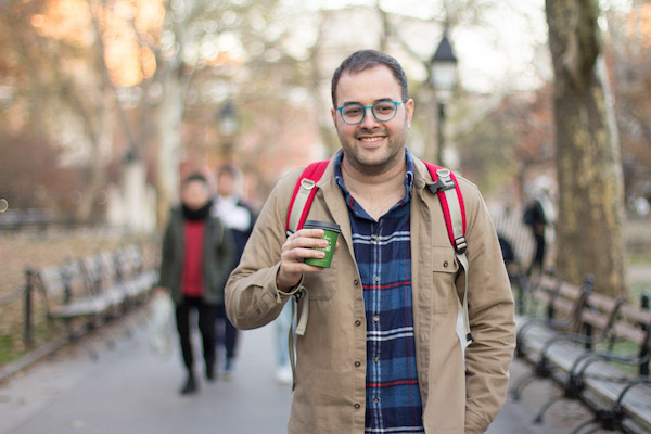 amir from cool cousin holds a coffee and smiles