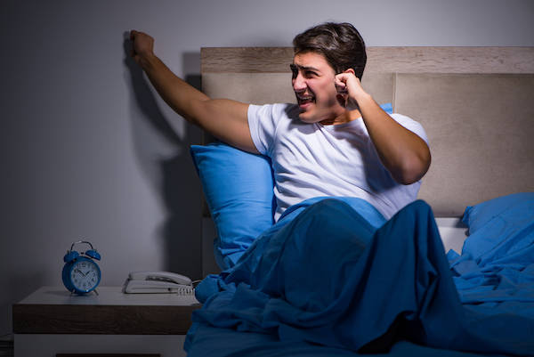 man in bed complaining about noisy neighbor