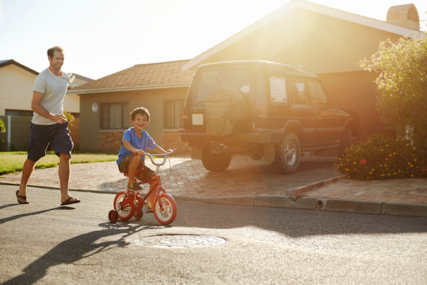 kid riding bike through neighborhood with dad