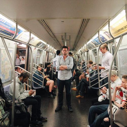 Justin from Cool Cousin stands in the middle of a subway car