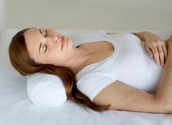 a woman lies down with a comfortable pillow in bed