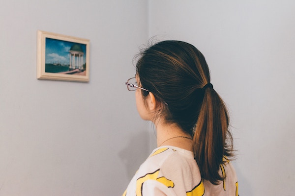 a woman approaches a work of art to examine it closer