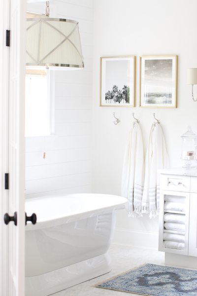 two tranquil art prints hang above turkish towels in a bathroom