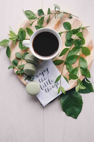 a round table with coffee, a card, and macaroons 