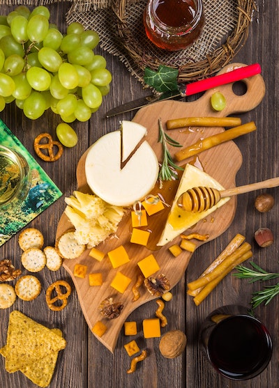 cheese, honey, and crackers on a wooden serving tray