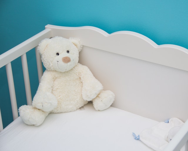 a white crib with a white stuffed bear