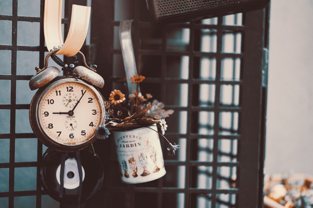 an antique clock hanging on a hook