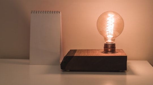 Clear lightbulb next to a white notepad on a white surface