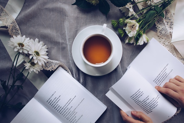 a book surrounded by a cup of tea and flowers