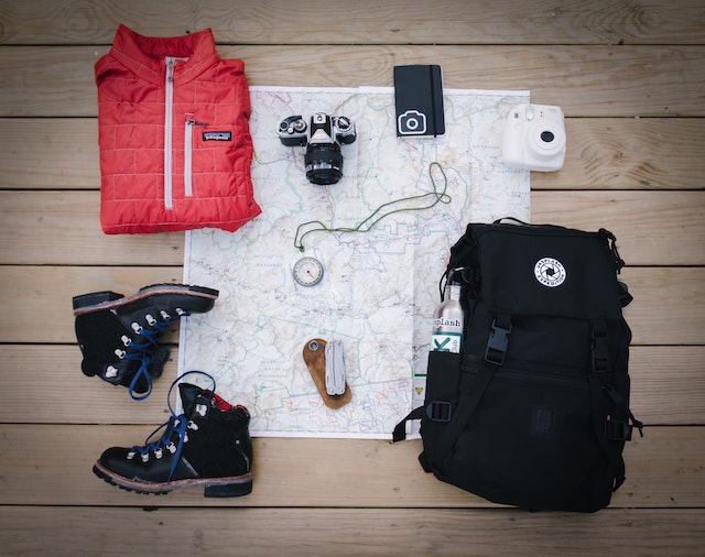 winter boots, jacket, camera and a backpack laid out
