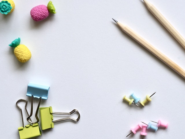 paper clips, pencils and erasers against a white backdrop