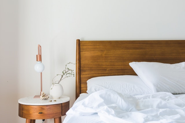 a messy bed with a night stand