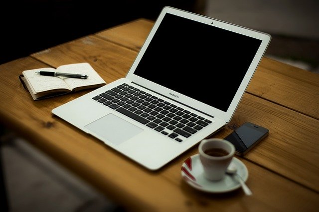 A computer and a cup of espresso on a wooden table