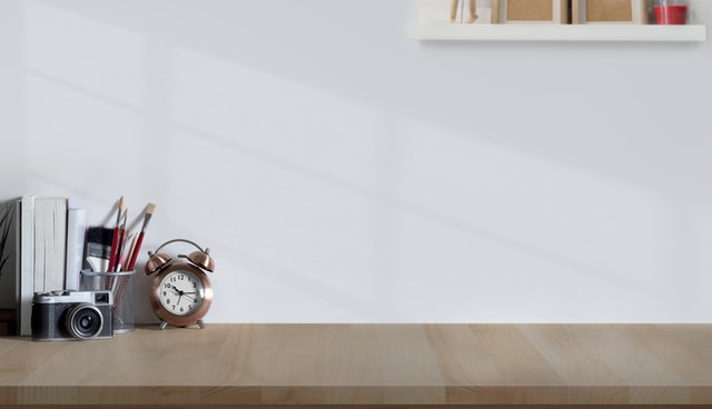 an empty shelf with a few essentials like alarm clock and pencils in a corner