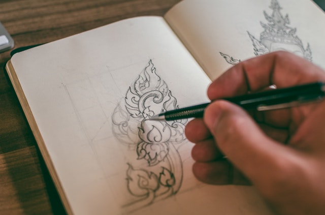 a person doodling art in a notebook